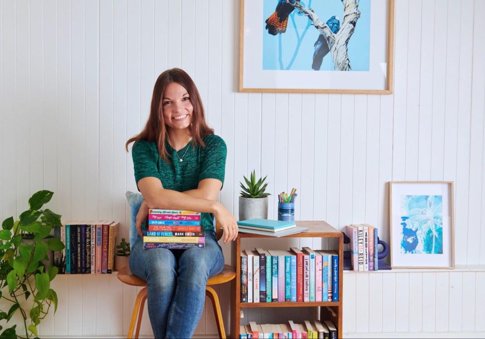 Young adult fiction author and ​​Australian Writers' Centre graduate Miranda Luby with a pile of books.